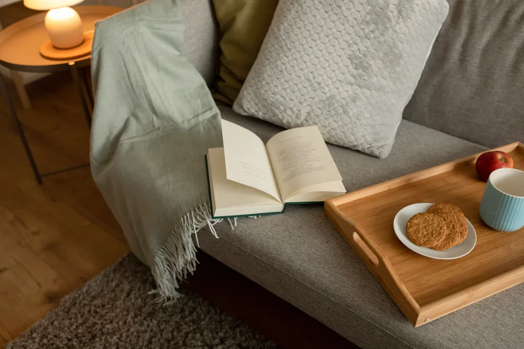 A book, a tray of food and tea on a couch. The Weekly Self-care activities