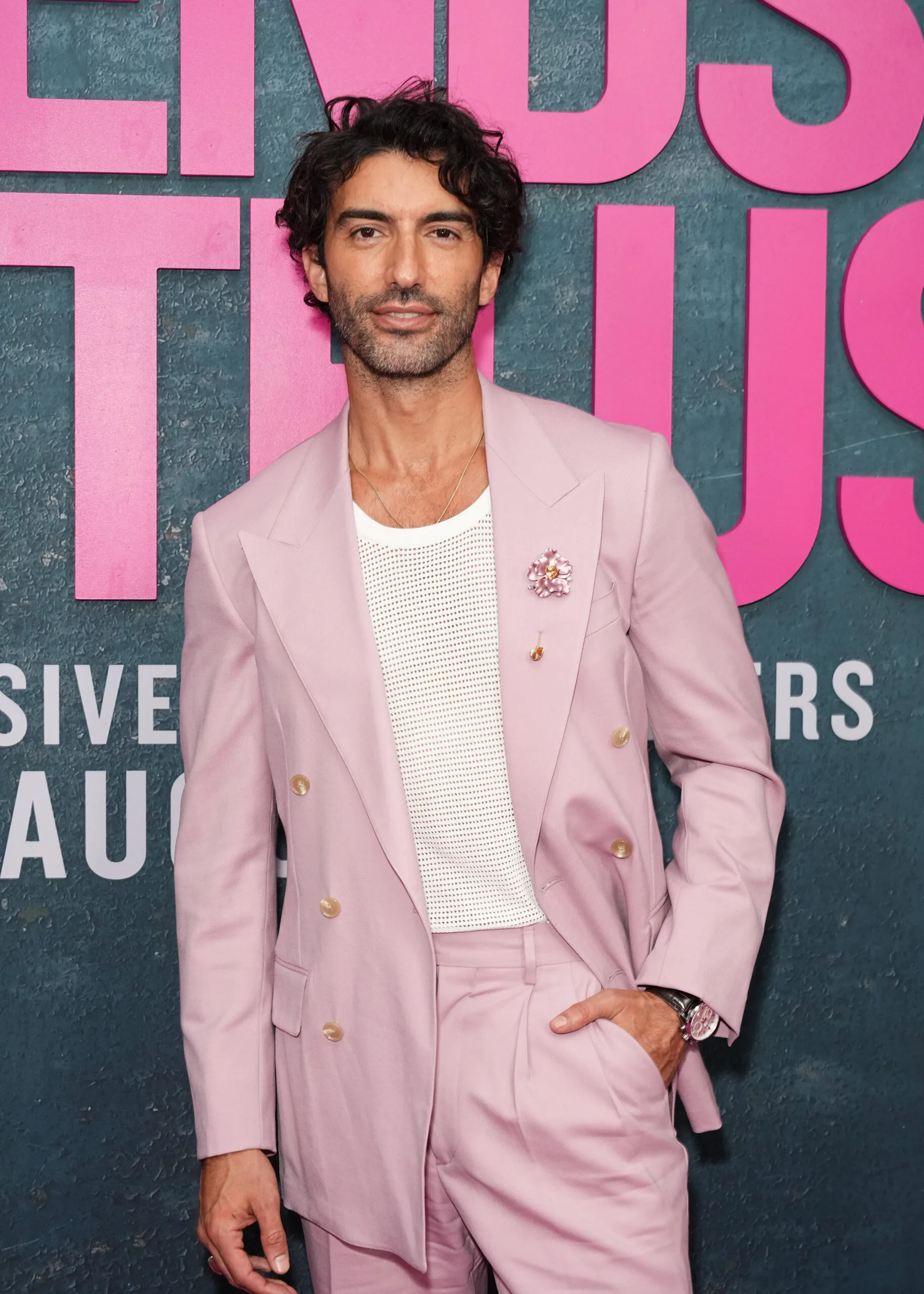 justin baldoni in a pink suit with a flower brooch at a screening of It Ends With Us