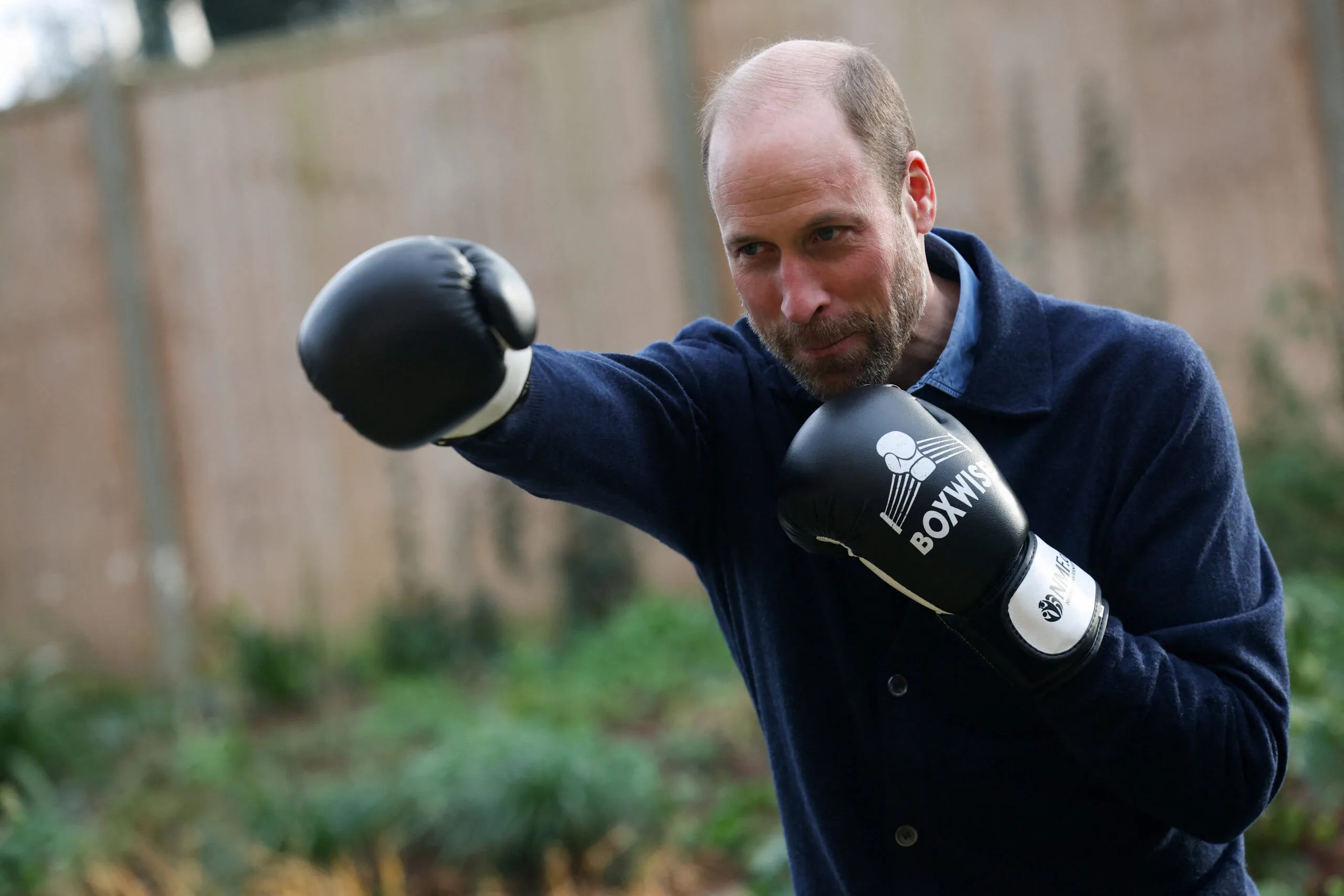 Prince William wear boxing gloves and making a punching gesture