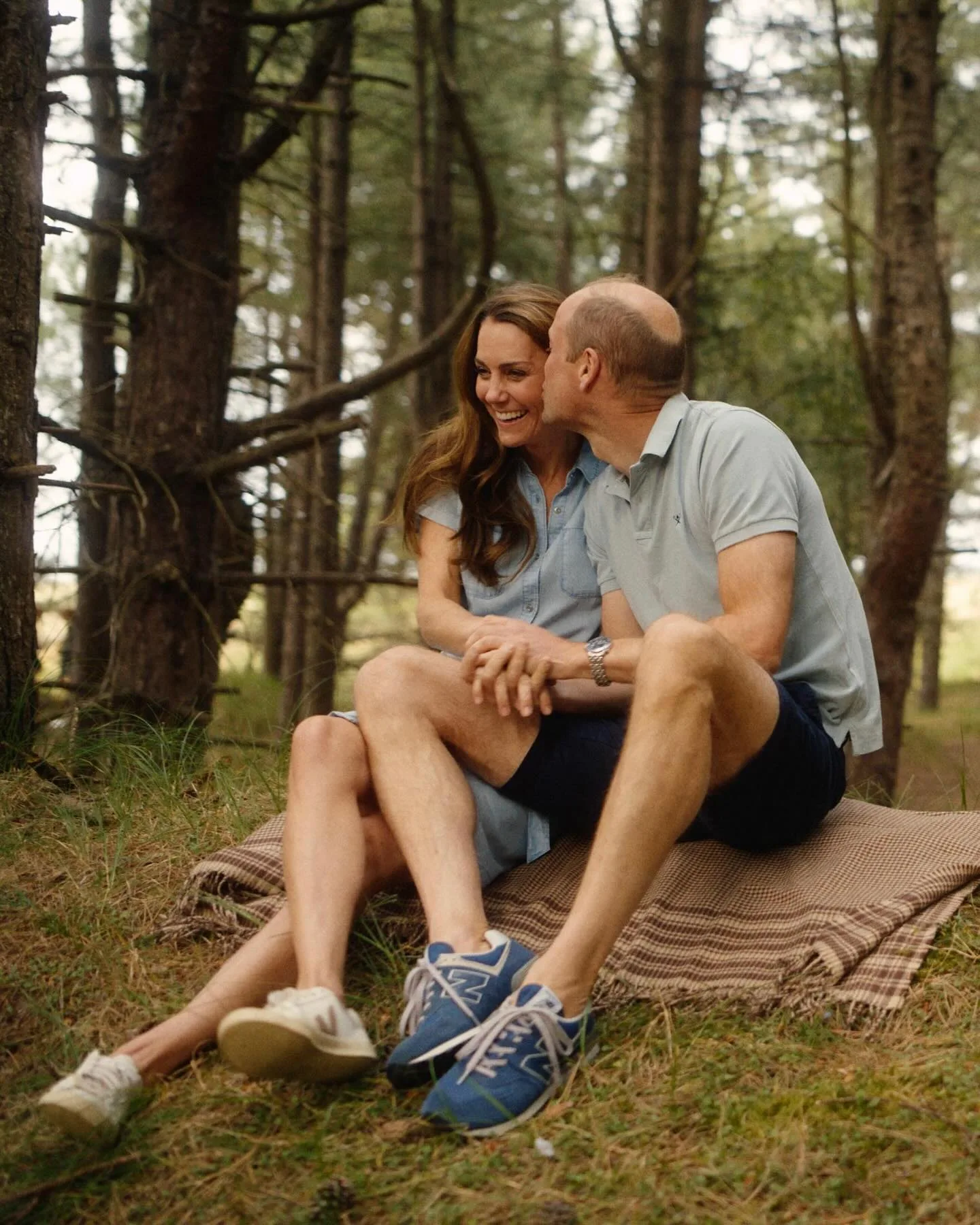 Prince William gives Princess Catherine a kiss on the cheek as they hold hands in the woods