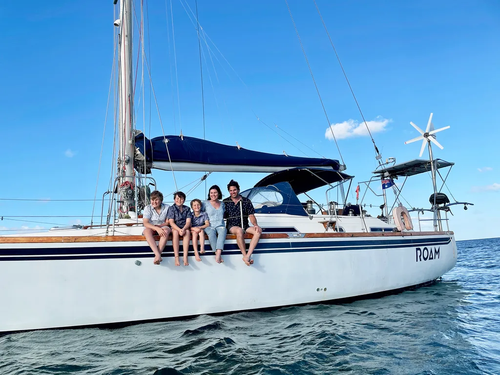A family of 5 sit on the edge of a small boat.