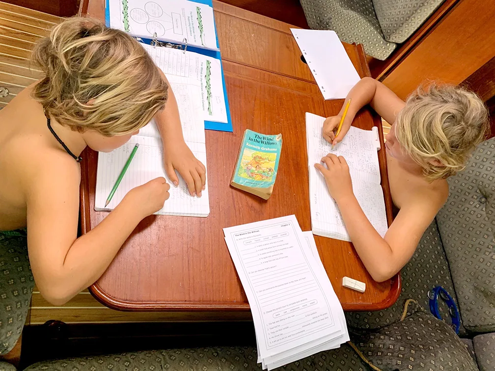 Two young white boys do homeschooling work at a table.