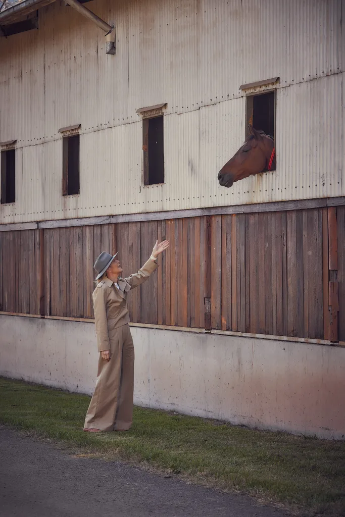 Katie Page, Harvey Norman CEO, talks to a horse peering out a stall window.