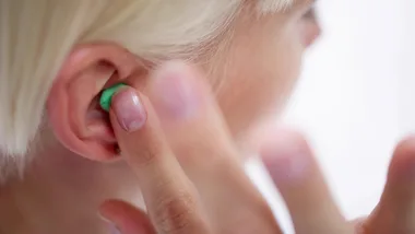woman placing an earplug into her ear