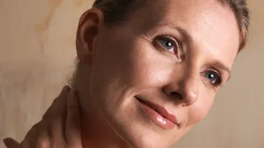 A beautiful mature-aged woman touching her skin.