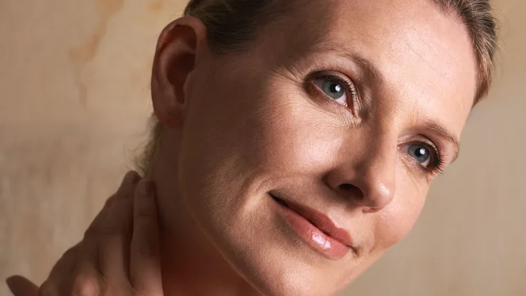 A beautiful mature-aged woman touching her skin.