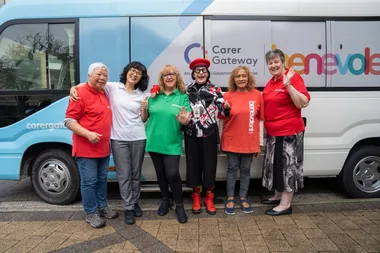 A group of women who are Greenwood Cottage volunteers stand in front of a bus