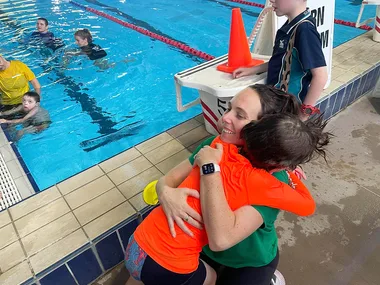 Mother Nicole hugs her son by a swimming pool