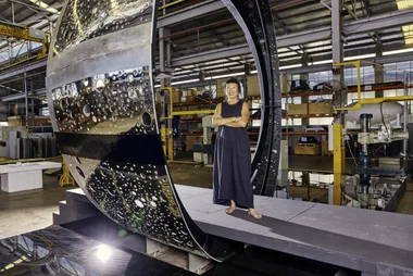 Chinese-Australian artist Lindy Lee stands with a section of her giant sculpture, Ouroboros.