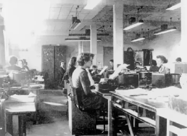 A black and white photograph of women sitting at typrewriters in an office space.