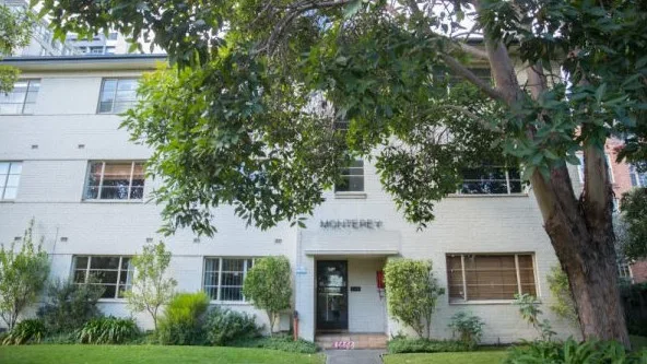 The Monterey apartment building today, with a cream coloured facade and a green front lawn.