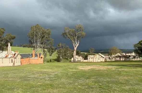 A homestead set amongst rolling green fields and gum trees.
