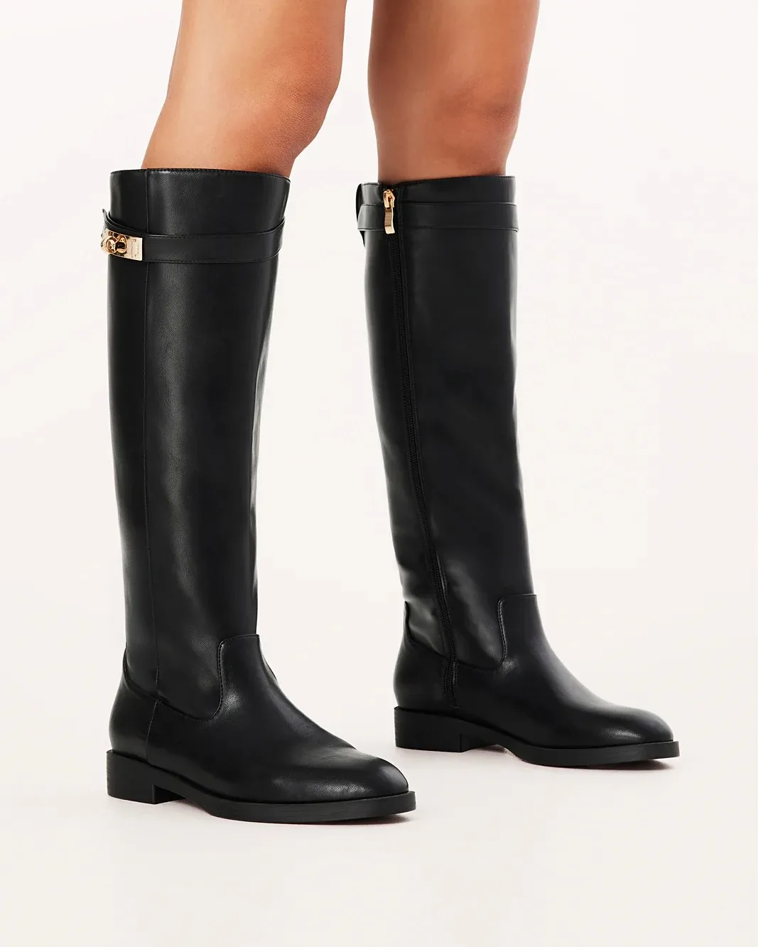 A pair of long black boots with a gold clasp