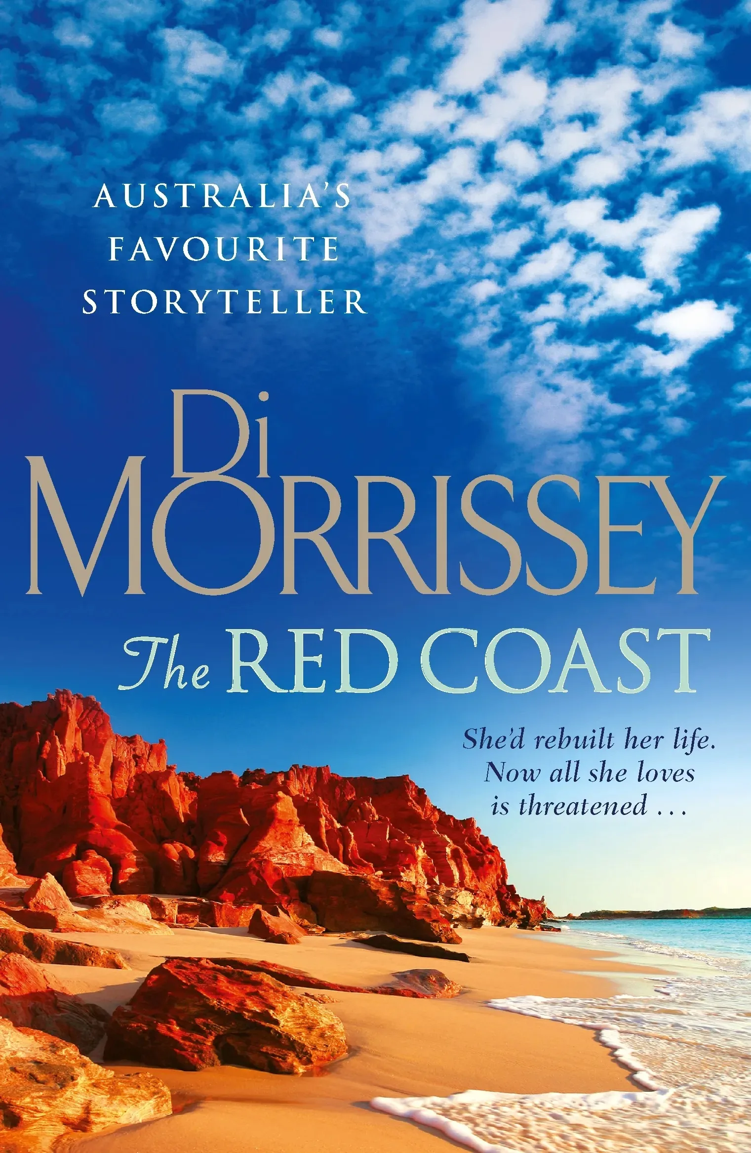 Di Morrissey books cover  - The Red Coast. A rocky read beach.