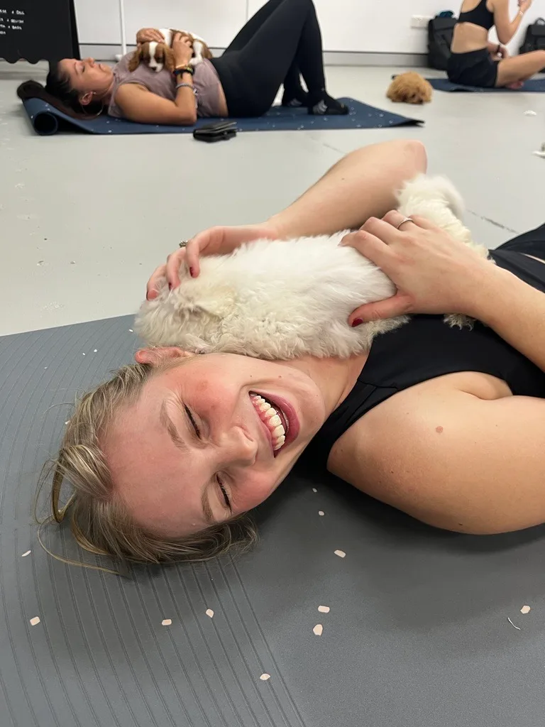 puppy yoga - woman smiling with puppy licking her face