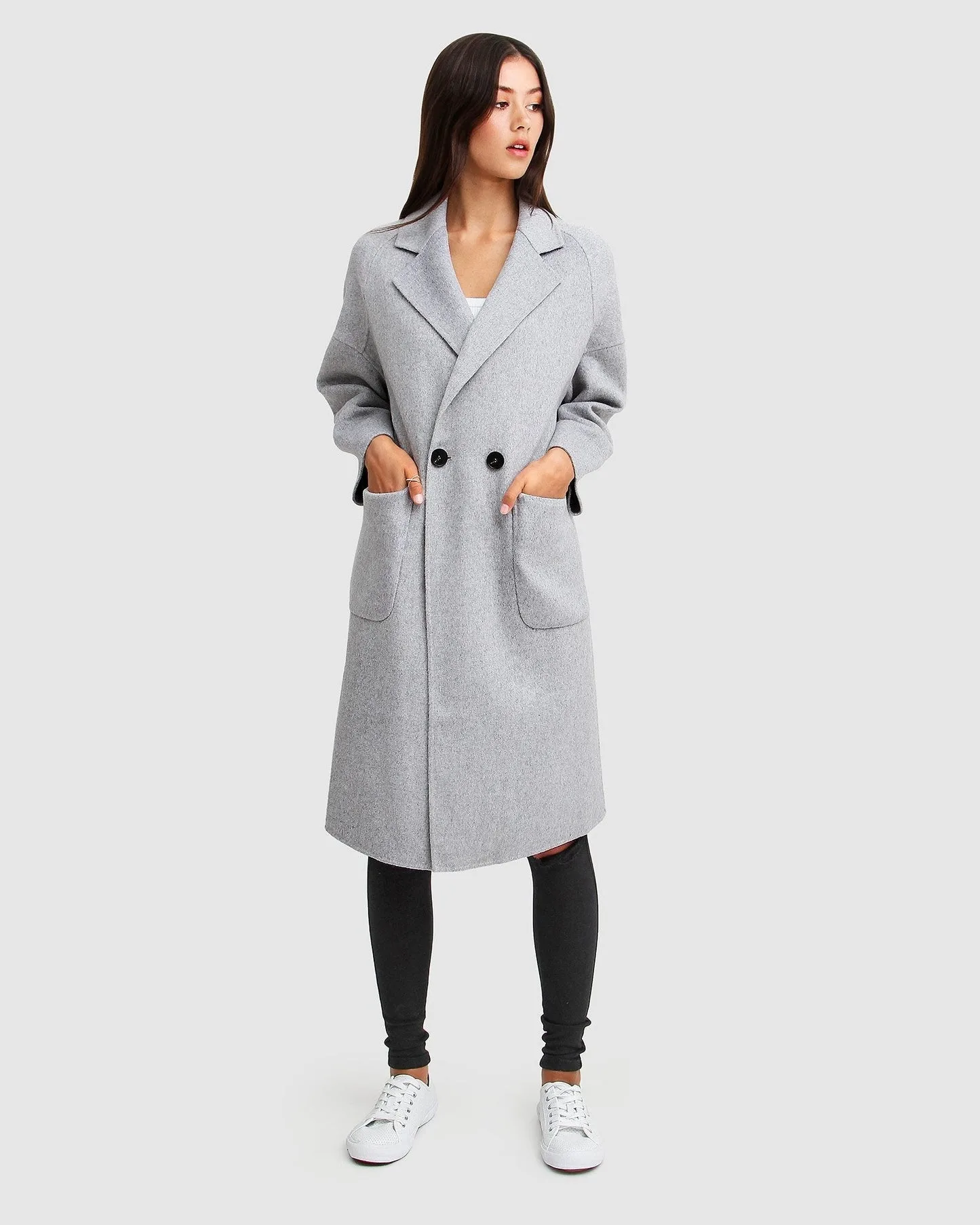 a woman wears a grey winter coat and black pants