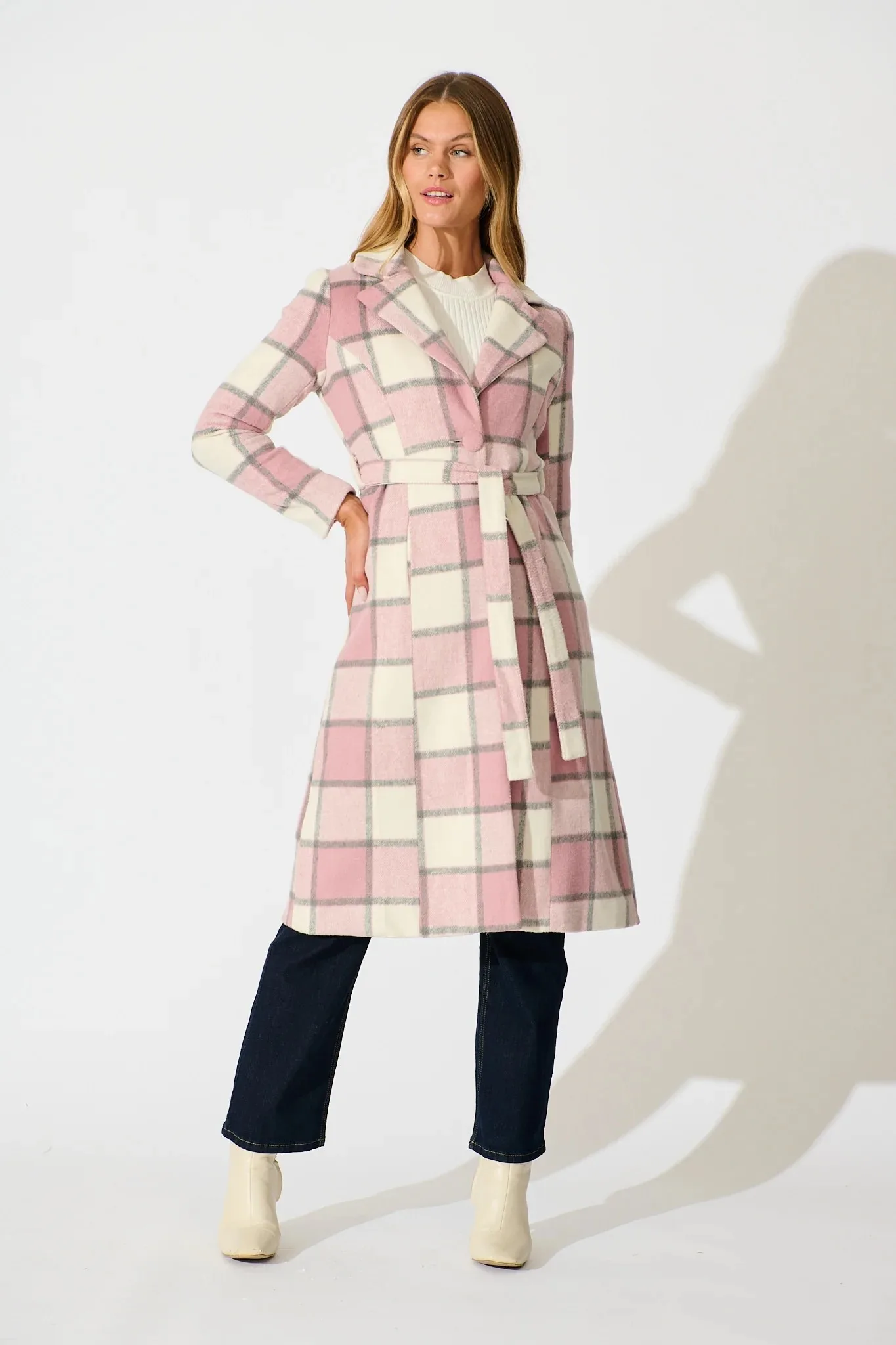 A white woman with blond hair wears a pink checked winter coat