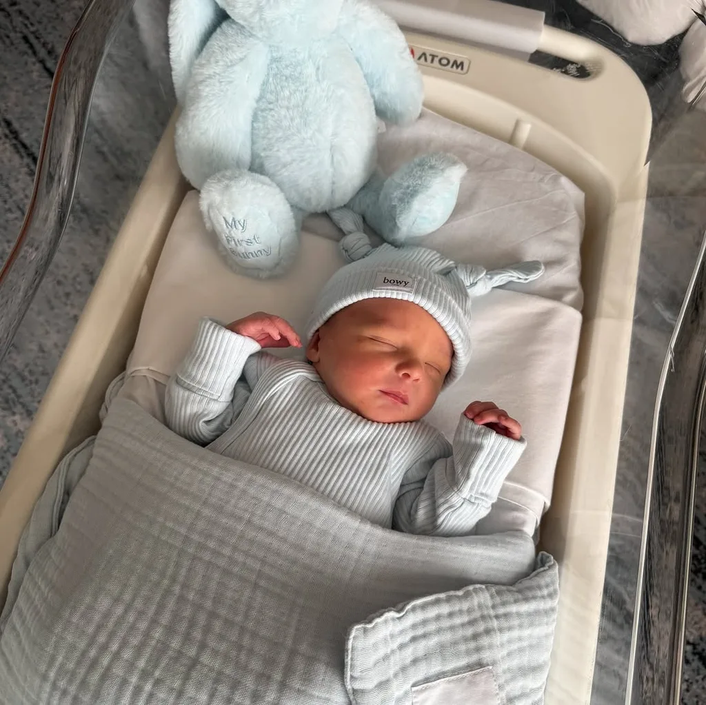 Abbey Holmes and her husband announce the birth of their baby. In the image a baby is sleeping in a crib.