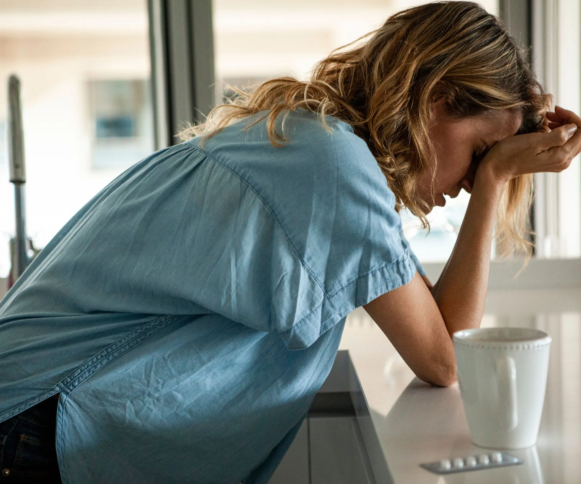 Women holding head in hands in kitchen
