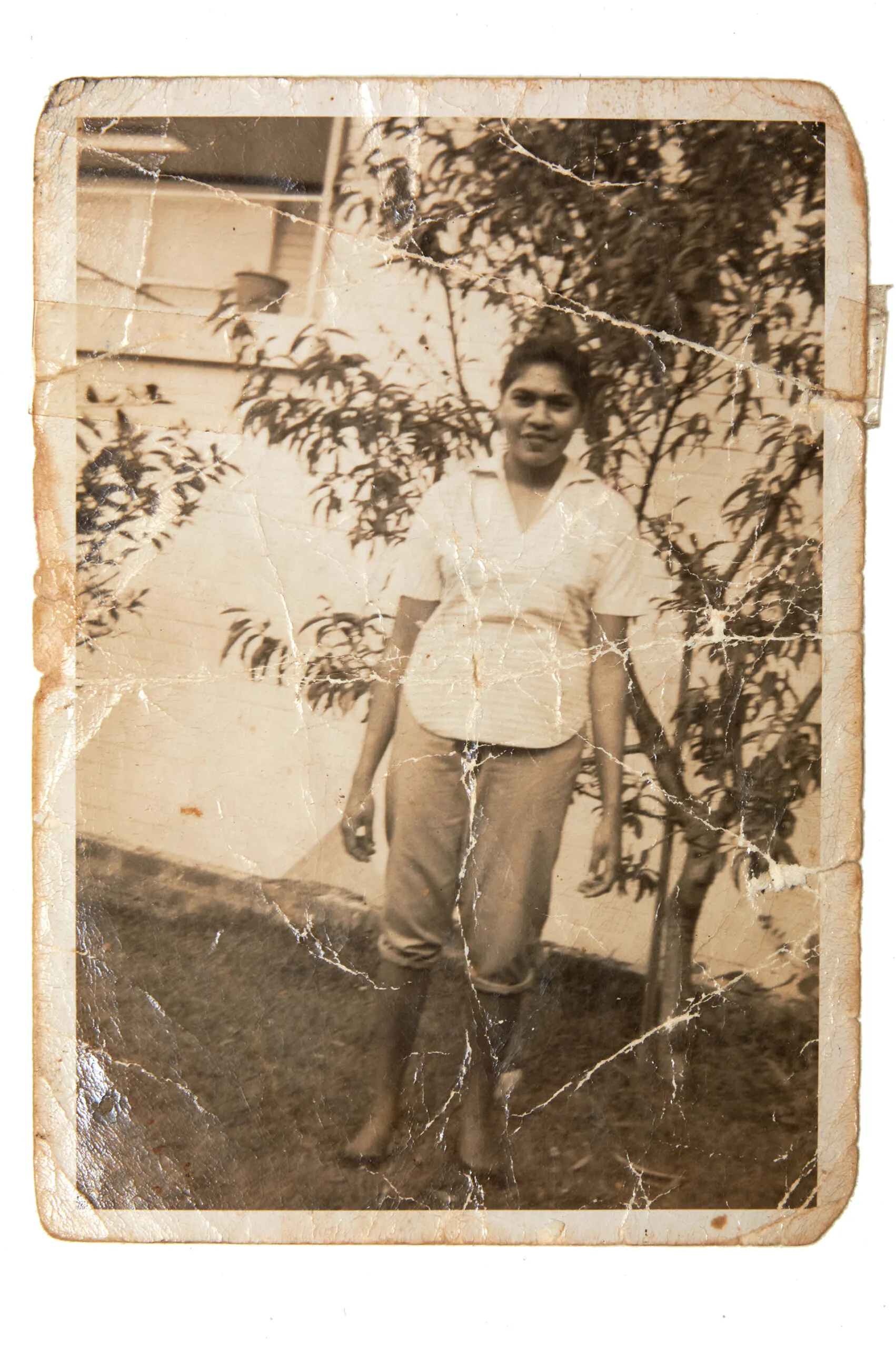 A black and white photograph of Aunty Beryl as a yound woman wearing jeans rolled up and a checked cotton shirt. Her hair is pulled back into a ponytail.