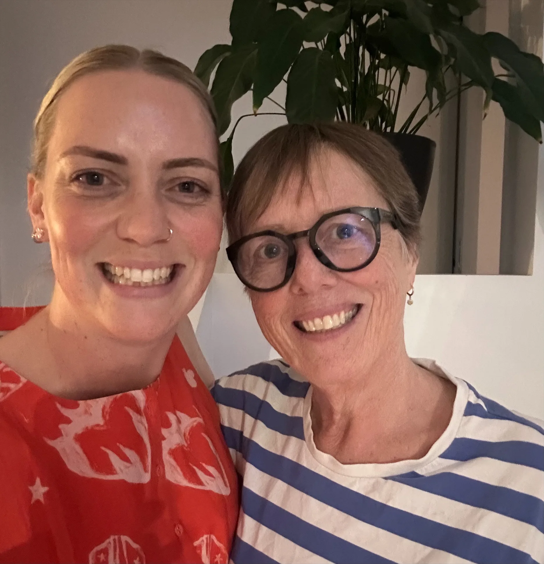 Susan (at right) has brown, short hair and wears glasses and a stripy blue top. her daughter Imogen (left) has her blond hair pulled back and wears a red and white print dress.