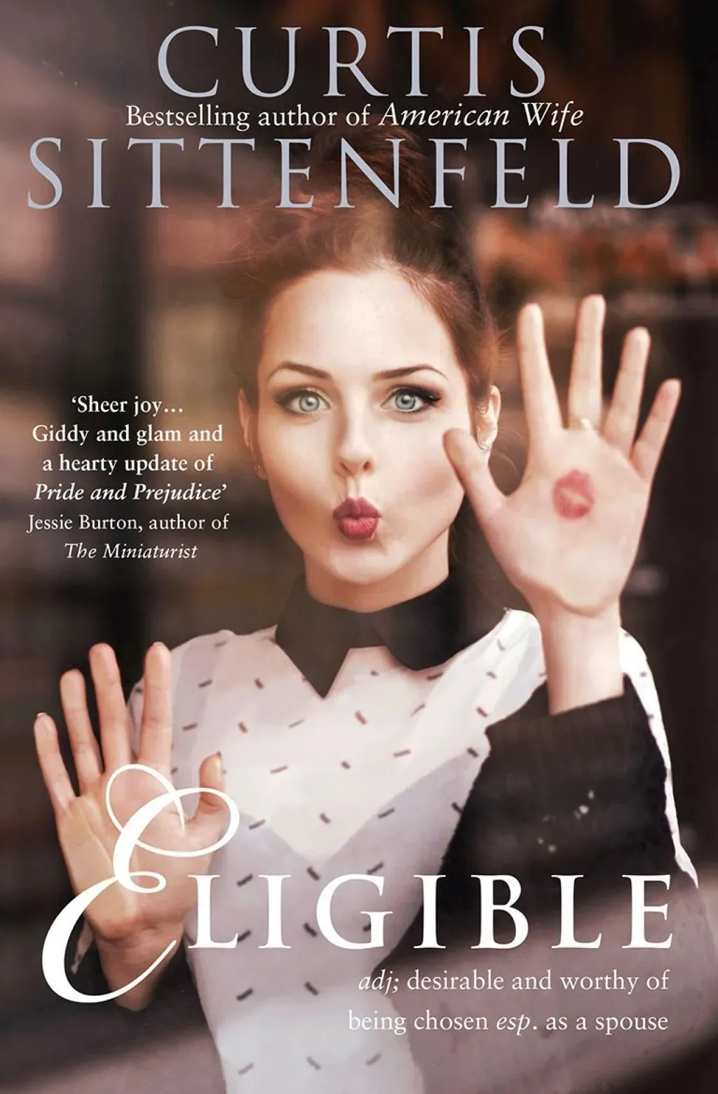 Book cover of Eligible by Curtis Sittenfeld, a retelling of Pride and Prejudice. A woman pictured through a pane of glass, blowing a kiss.
