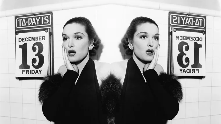 black and white image of a woman looks scared next to a calendar displaying the date Friday the 13th