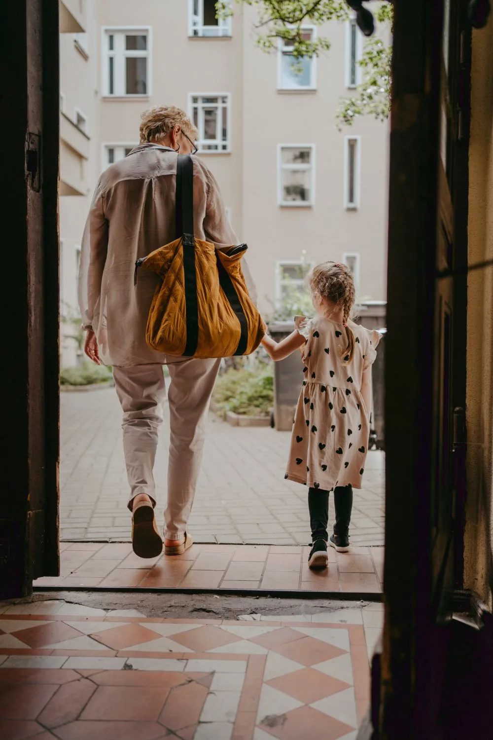 Mature woman holding young girl hand through doorway