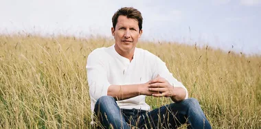 singer James Blunt sits in a grassy field
