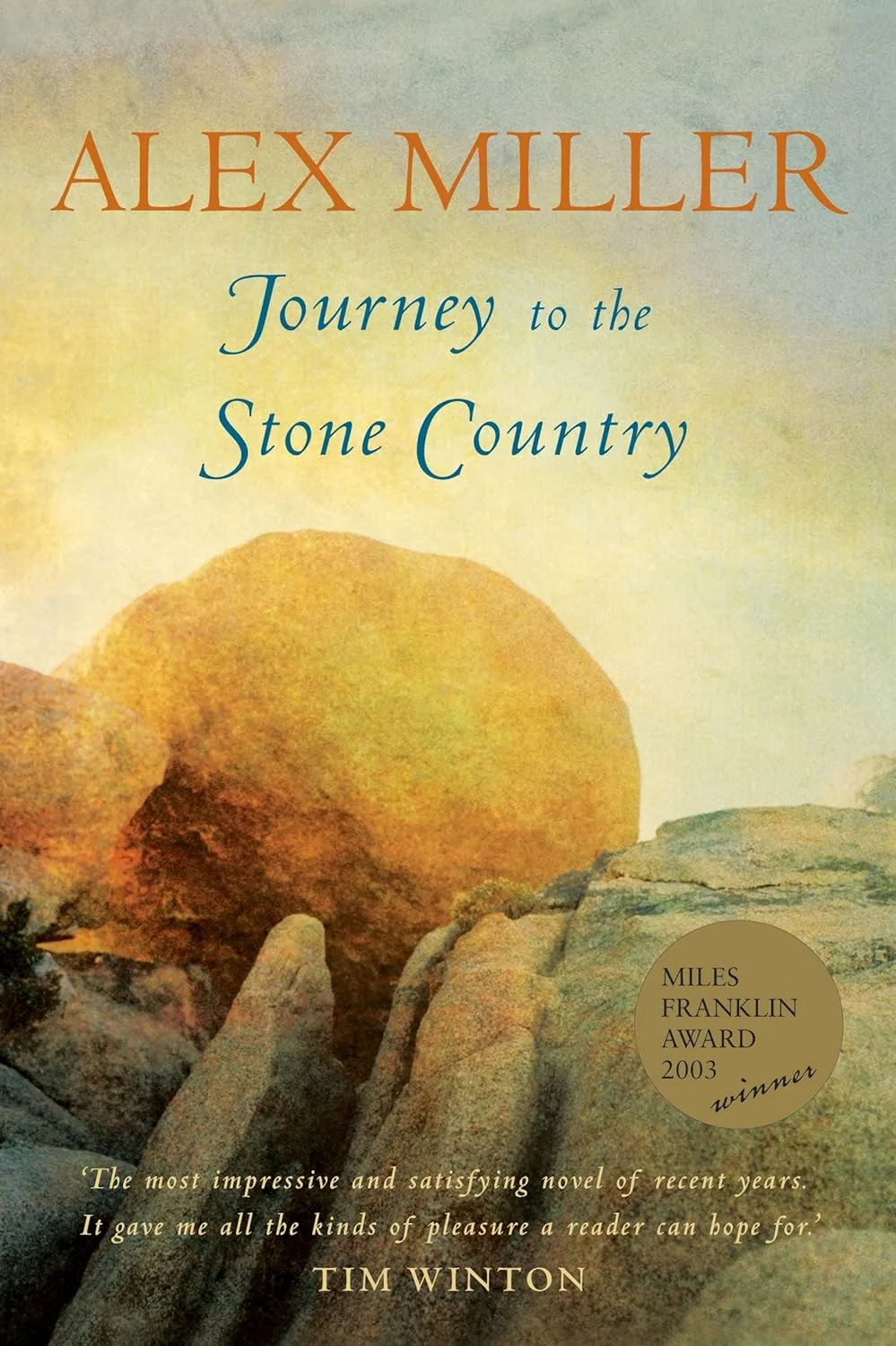 Book cover Journey to the Stone Country by Alex Miller. A photo of rocks glowing yellow.