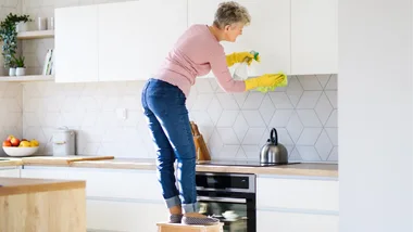 older woman cleaning kitchen cupboards