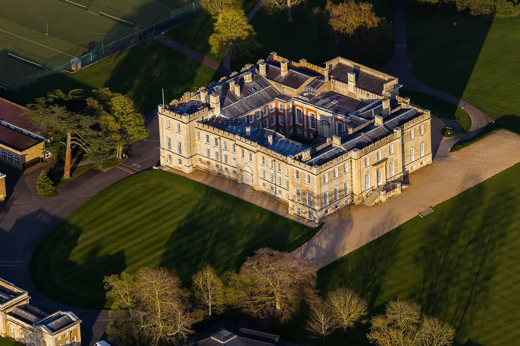 Aerial photo of a three-storey castle in pale brick. Kimbolton Castle.
