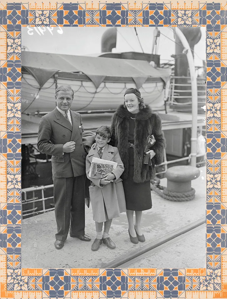 Duke Mandy, the young boy Sidney, and Australia's forgotten duchess, Nell Stead, stand on a dock with a young boy between them. Behind them is a boat.