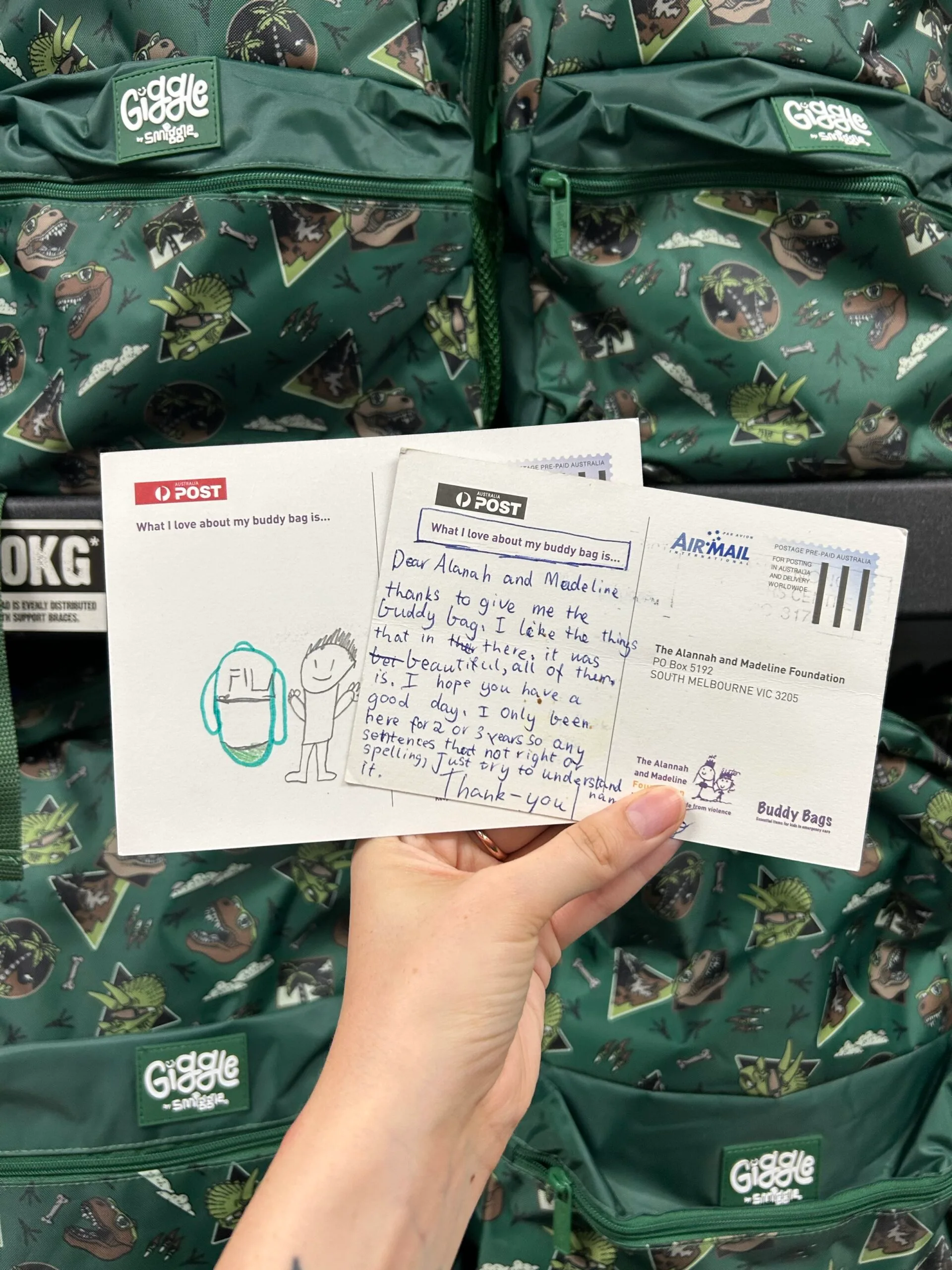 A green Buddy Bag and a card from a recipient which reads: 'Dear Alannah and Madeline, thanks to give me the buddy bag. I like the things that in there. It was beautiful, all of them. I hope you have a good day. I only been here for 2 or 3 years, so any sentences that not right or spelling, just try to understand it. Thank you.'