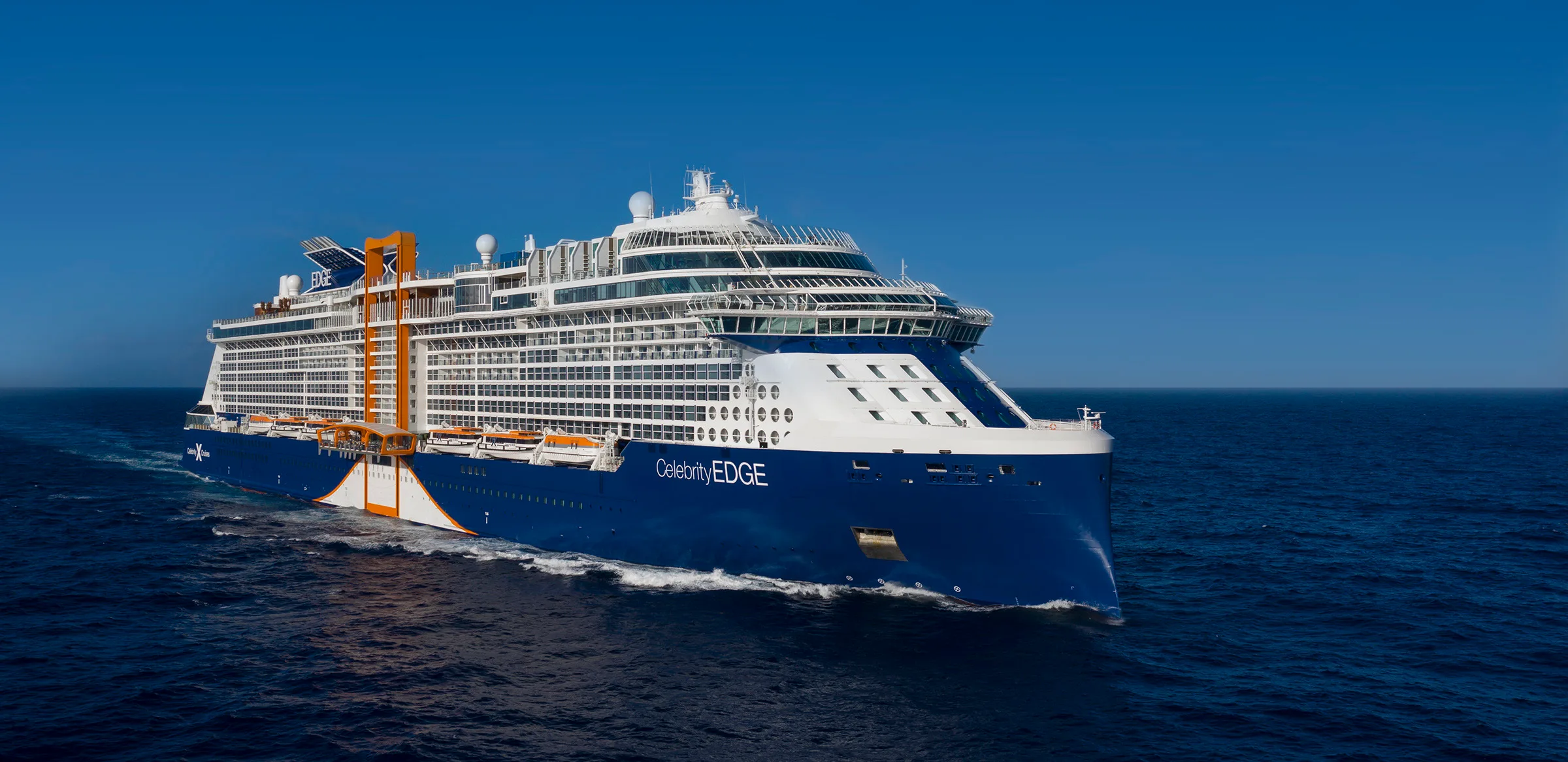 The Celebrity Edge ocean cruiser ploughs through a calm sea.