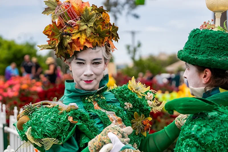 A person dressed up in a floral costume made of fake leaves, grass and animals.