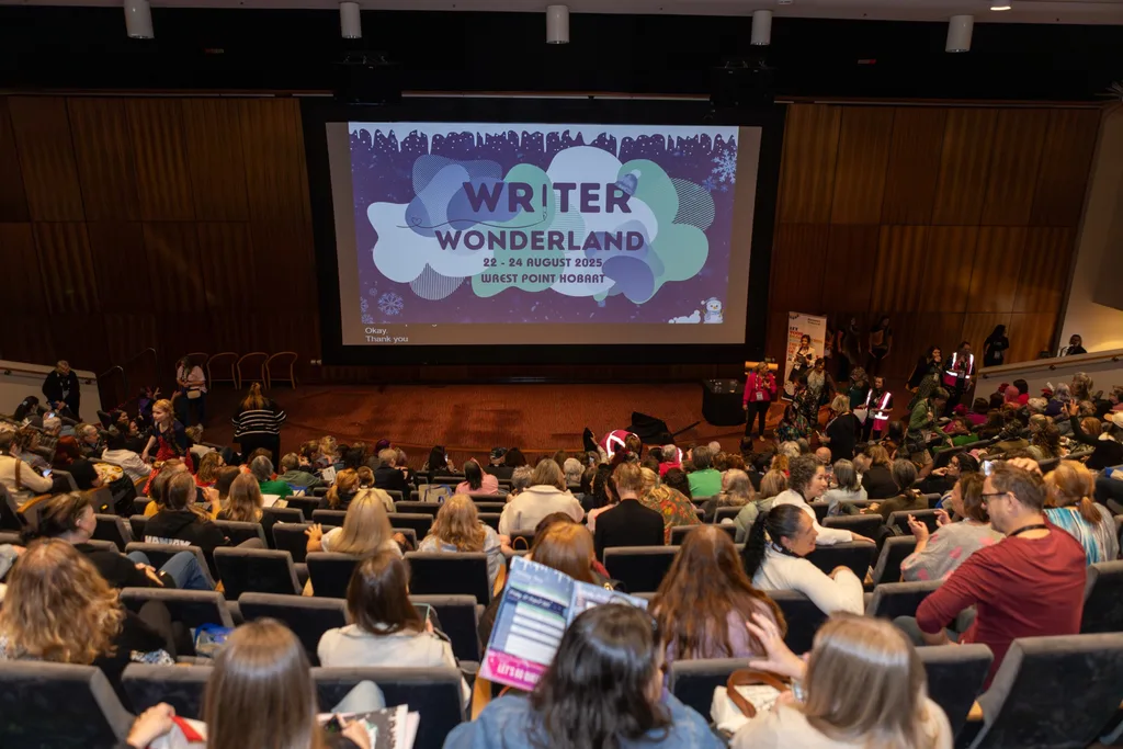 People seated in an auditorium in front of a screen.