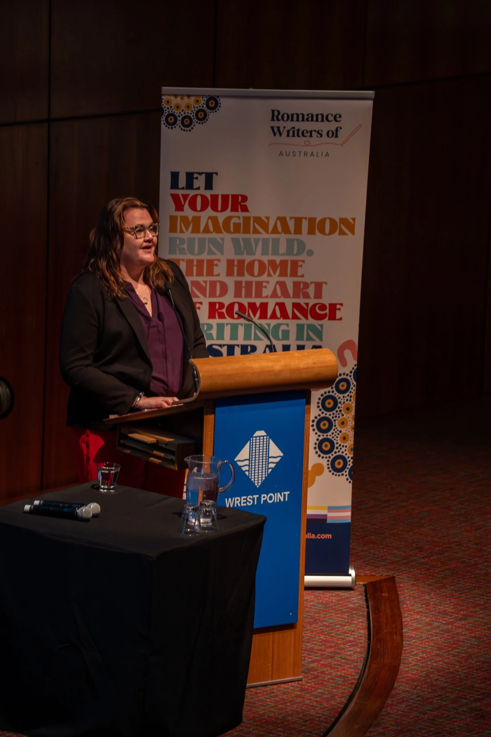 romance author Sarah MacLean speaking at a lectern.