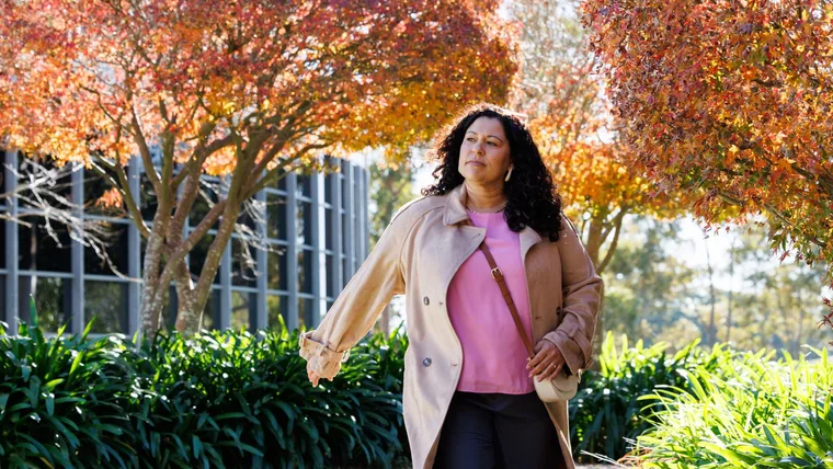 Women in jacket walking down the street with autumn trees