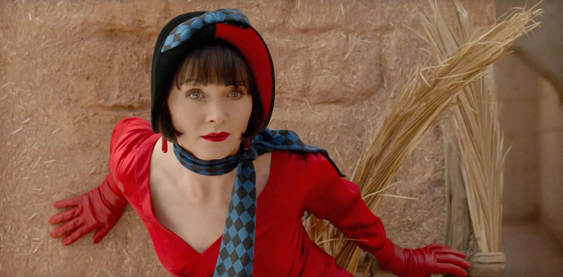 Essie is dressed as Phryne in a 1920s hat, res dress and matching gloves, and a blue checked scarf.