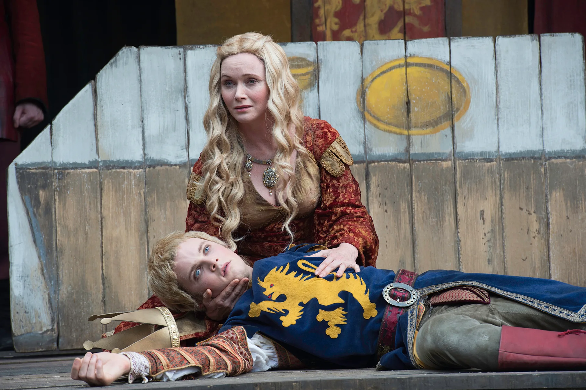 Essie wears a long blonde wig and medieval dress. She kneels beside an actor playing a dying man.