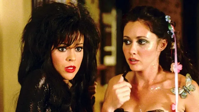 Two women stands side by side, dressed in Halloween costumes.