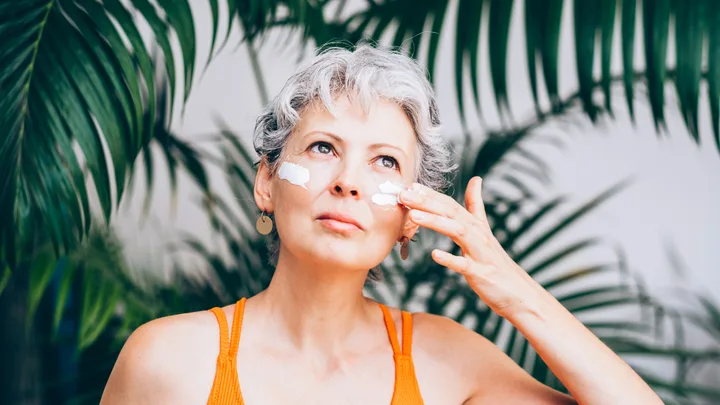 woman applying skincare outside