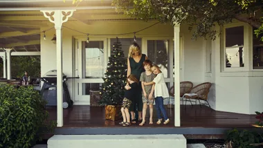 Women and children in front of house at christmas