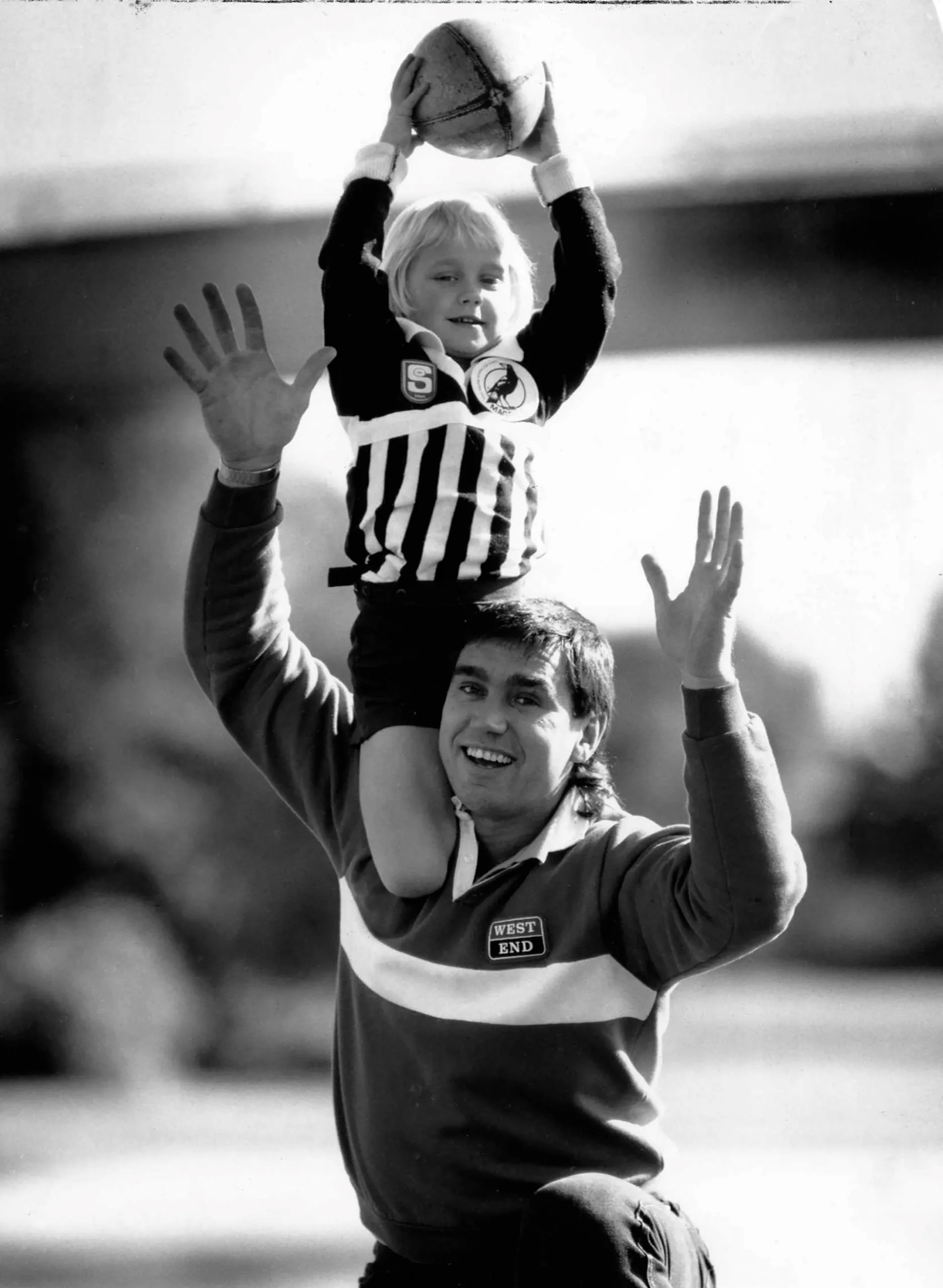 JULY 18, 1990: ADELAIDE, SA. Erin Phillips, 5 years old, takes a mark over dad footballer Greg Phillips in Adelaide, South Australia. (Photo by Phil Hillyard / Newspix)