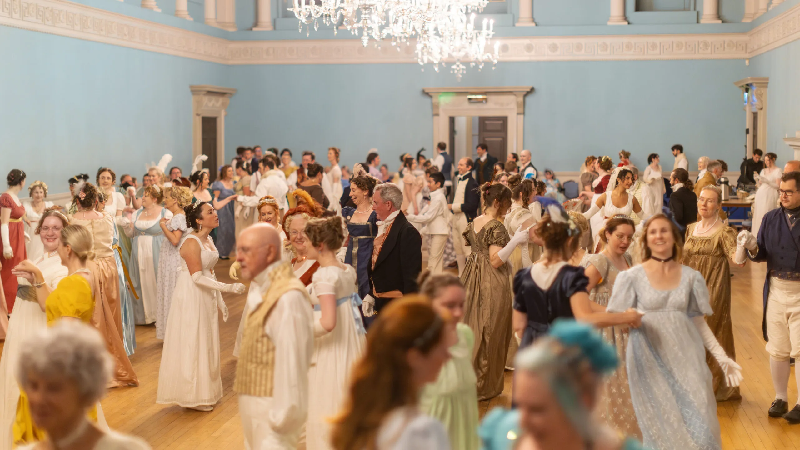 Jane Austen fans in regency costume at a ball.
