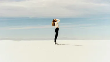 woman standing on sand holding her face in her hands