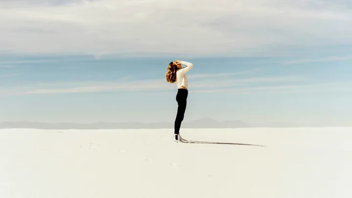 woman standing on sand holding her face in her hands