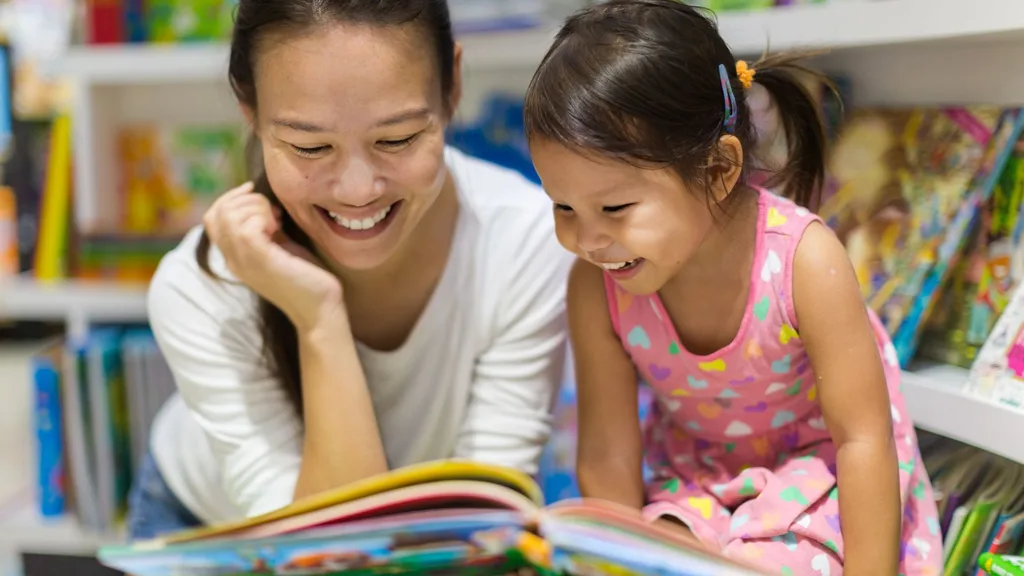 An Asian mother reads a picture book to her daughter.