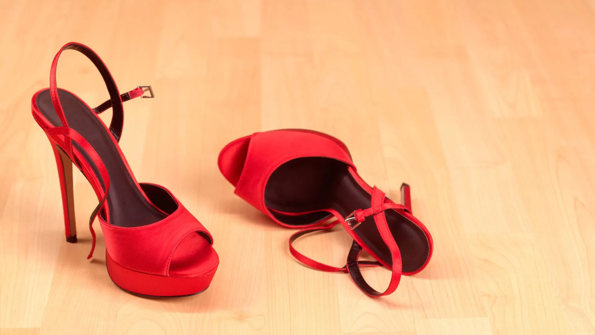 A pair of red high-heeled platform heels discarded on a wooden floor, illustrating the search for the most comfortable heels Australia women actually want to wear.